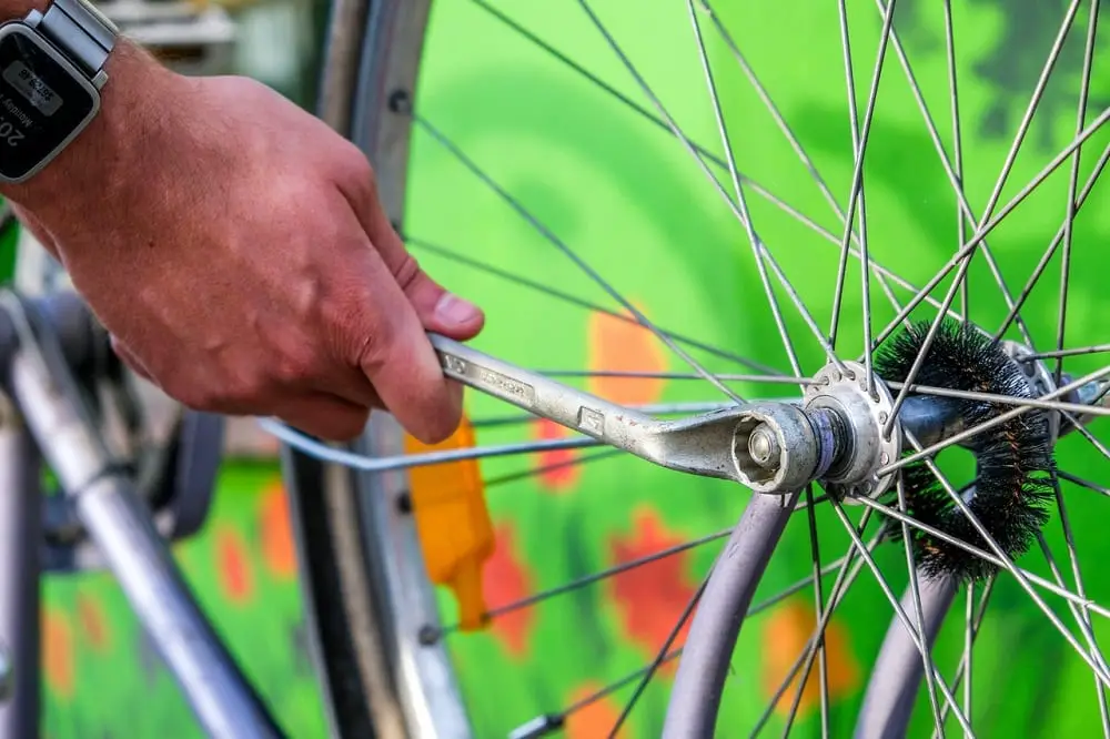 man tightening bicycle rear wheel screw
