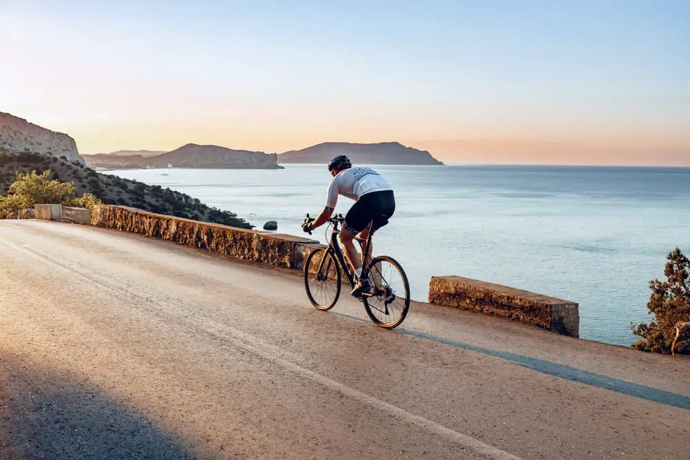 cyclist pedaling on a road bike outdoors in sun set Gravel Bike Vs Road Bike